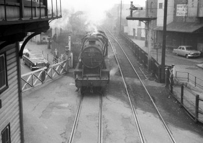 A stanier 8f 48619 is just moving across the High Street level crossing